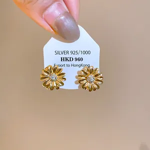 Detalle de los elegantes pendientes de margarita chapados en oro de 18k con circonitas