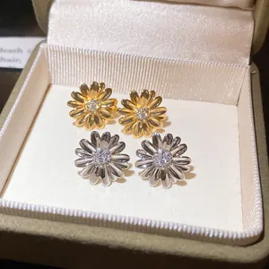 Primer plano de elegantes pendientes de margarita en oro y plata con circonitas