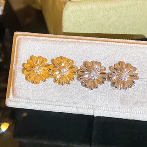 Detalle de pendientes de margarita elegantes en acabado oro y plata con centro circón