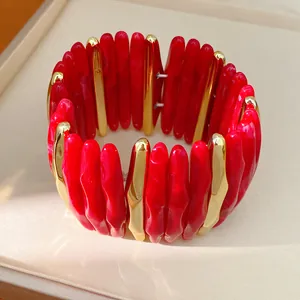 Close-up of red marbled acrylic and gold-toned metallic segment stretch bracelet