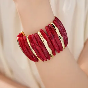 Detailed view of a red marbled acrylic and gold wavy segment stretch bracelet on wrist.