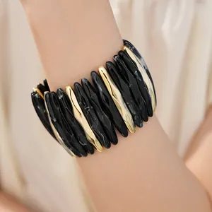 Macro detail shot of marbled acrylic stretch bracelet accented with metallic gold bars.