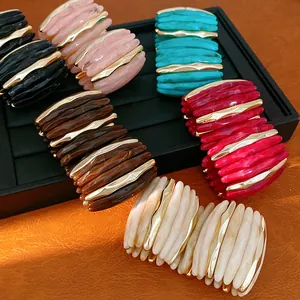 Detailed view of colorful marbled acrylic bracelets with metallic accents on a jewelry tray