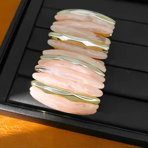 Detailed close-up showing pink marbled acrylic segments and gold wavy accents on bracelet