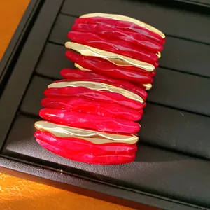 Macro detail of red marbled acrylic and gold wavy metal elastic bracelet segments