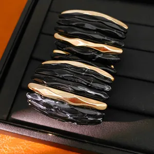 Close-up of acrylic marbled and gold-tone segmented elastic bracelet for women.