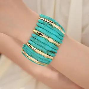 Detail view of a stylish marbled turquoise and gold elastic acrylic bracelet on a model wrist.