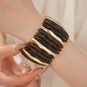 Close-up of marbled acrylic and gold-tone segmented elastic bracelet worn on wrist