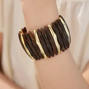 Close-up detail of a marbled brown acrylic and gold-toned stretch bracelet on a wrist