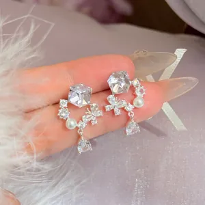 Elegante zilveren oorbellen met zirkonia bloem en druppel hanger getoond op handdisplay