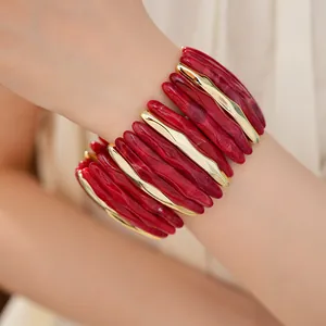 Close-up of marbled red acrylic and gold metal segments on a wide elastic bracelet