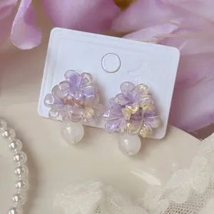 Prachtige close-up van paarse zirkoon bloemenoorbellen met elegante witte druppelkralen