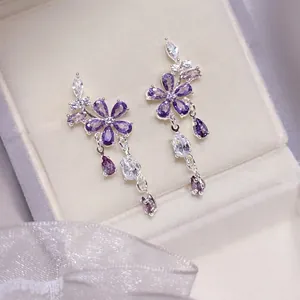 Elegante paarse zirkoon bloem oorbellen met traanhangers op een wit juwelendoosje
