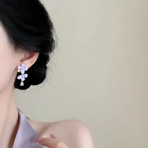 Detailopname van elegante paarse bloem oorbellen met zirkoon waterdruppel hanger aan het oor