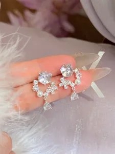 Luxe detailopname van zilveren bloemoorbellen met glanzende zirkonia en witte parels