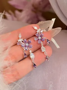 Gedetailleerde close-up van elegante paarse zirkoon bloem hangoorbellen met zilveren steker