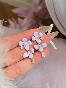 Detailweergave van elegante paarse lavendelbloemenoorbellen met zirkonia en parels