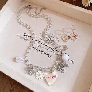 Vue détaillée d'un ensemble collier et boucles d'oreilles marguerite cœur sur un plateau