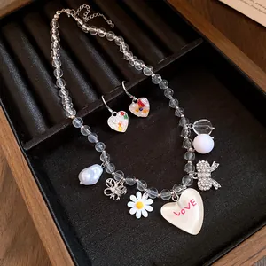 Gros plan d'un ensemble collier et boucles d'oreilles cœur et marguerite.