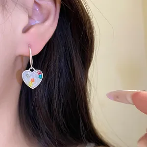 Vue détaillée d'une boucle d'oreille cœur avec des éclats d'incrustations colorés.