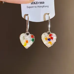 Gros plan de boucles d'oreilles en forme de cœur avec perles colorées sur étiquette