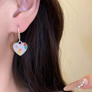 Gros plan d'une boucle d'oreille en forme de cœur avec mosaïque colorée sur un mannequin.