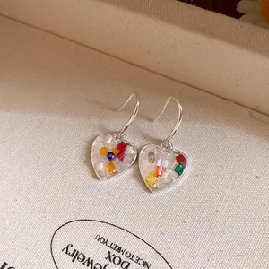 Vue détaillée de boucles d'oreilles en cœur remplies de perles colorées vives