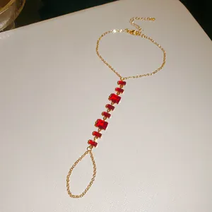 Vue macro montrant la chaîne dorée complexe et les pierres de zircon rouges du bracelet