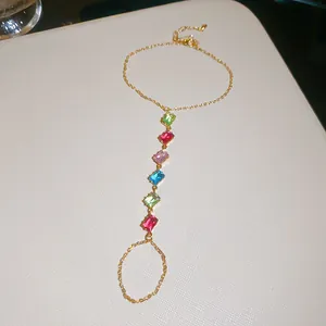 Zoom sur le bracelet bague en zircons multicolores avec chaîne dorée élégante et chic.