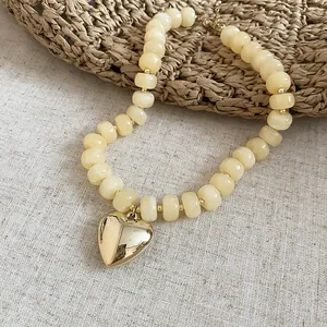 Primo piano di un ciondolo a cuore su una collana di perle acriliche color caramella