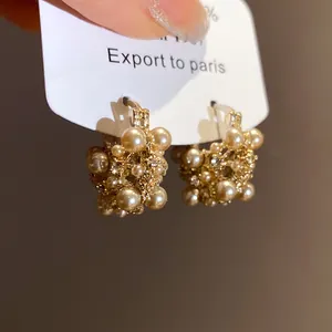 Detailed view of vintage hollow gold-tone earrings with elegant clustered pearl accents
