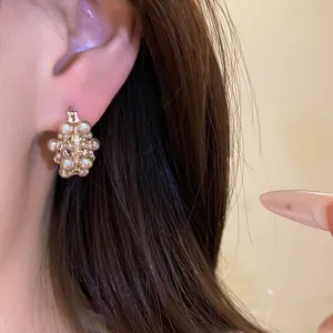 Detailed view of elegant French vintage hollow basket earrings with pearls on ear