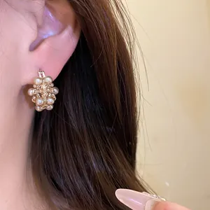 Detailed view of an elegant French vintage hollow pearl basket earring worn on an ear
