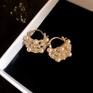 Detailed macro shot of French vintage hollow pearl flower basket hoop earrings for women