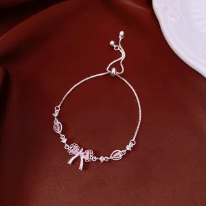 Detailed macro shot of silver bow bracelet with pink zircons on elegant dark fabric
