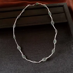 Detail view of silver wire mesh necklace with green crystal beads on black display tray
