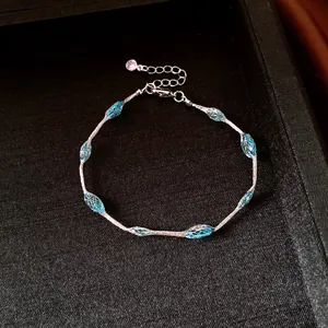 Detailed view of silver chain bracelet featuring blue mesh oval beads in a jewelry box.