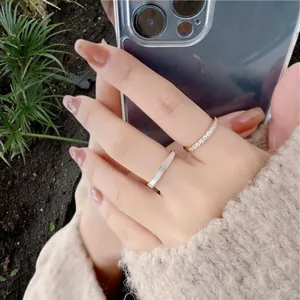 Détail d'une bague dorée sertie de zircons et d'une bague en nacre sur un doigt