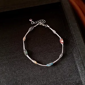 Close-up of rainbow beads inside silver mesh cage on a minimalist chain necklace.