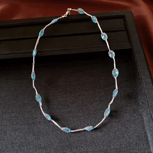 Detailed view of minimalist necklace with blue beads and silver mesh on black display.