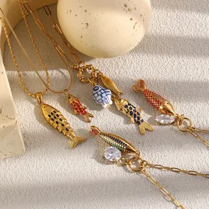 Primer plano de colgantes de peces bañados en oro de 18K con esmalte y cristales