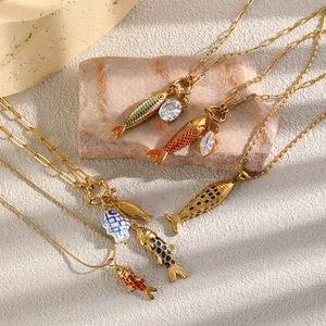 Detalle de collares de acero chapado en oro de 18K con colgantes de peces en esmalte de colores.
