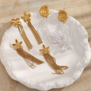 Detail of gold-plated flower and shell tassel earrings with pearls and chains