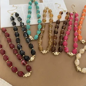 Macro detail shot showing various colors of twisted acrylic oval beaded necklaces on a table