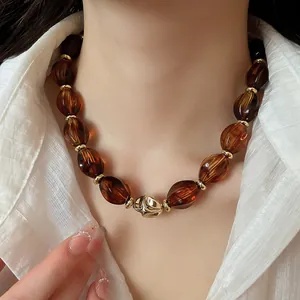Detail shot of amber acrylic oval bead choker featuring a twisted gold accent bead