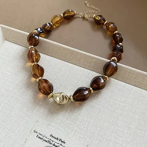 Close-up of vintage amber acrylic twisted beads and gold hardware necklace detail.