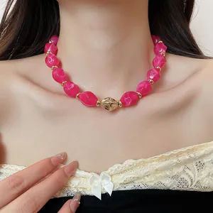 Close-up of a vibrant pink twisted acrylic bead necklace with gold-toned accent pieces
