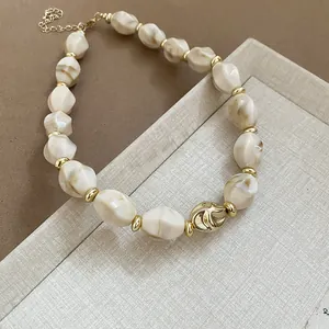 Detail view of a chunky acrylic marbled bead necklace with gold-toned spacers and chain