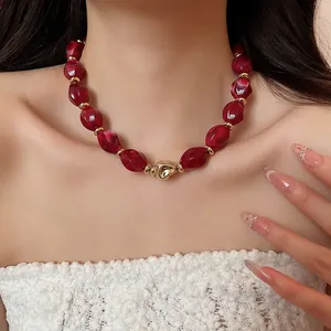 Close-up detail of deep red acrylic oval twisted necklace worn on a woman's neck