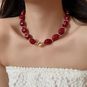 Detail view of red acrylic oval twisted necklace with gold accents for trendy women